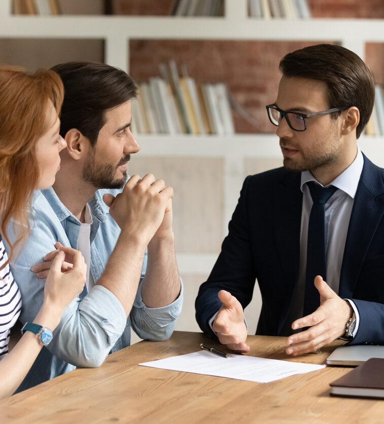Interested young family couple visiting financial advisor in office.